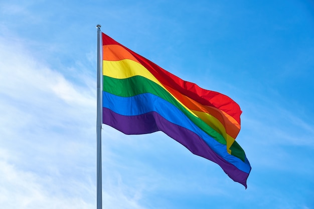 bandeira LGBT contra um céu azul nublado.