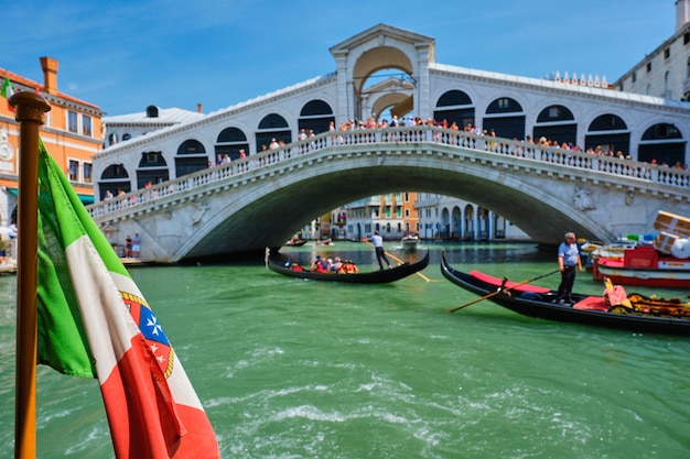 Foto bandeira marítima italiana com ponte de rialto com gôndolas no bacground. grand canal, veneza, itália
