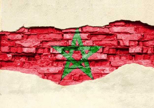 Bandeira nacional do Marrocos em um fundo de tijolo. Parede de tijolos com gesso, fundo ou textura parcialmente destruída.