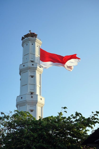 Foto bandeira nacional indonésia em farol com fundo de céu azul