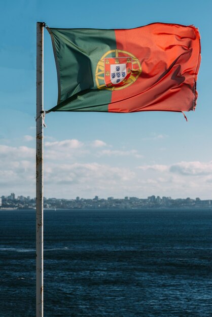 Foto bandeira portuguesa com cascais portugal no fundo ao lado do mar