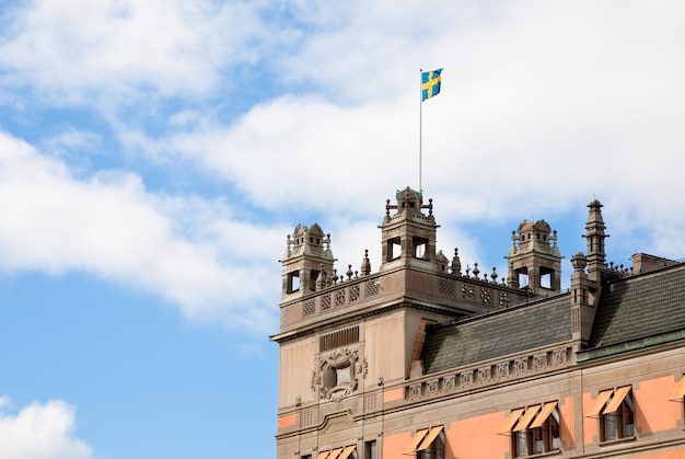 Bandeira sueca no telhado da velha casa em Estocolmo