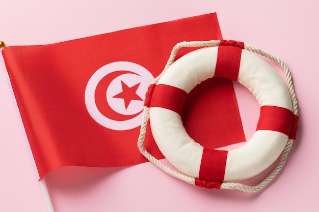 Bandeira tunisiana e bóia salva-vidas em um conceito de fundo colorido sobre o tema de ajudar a Tunísia