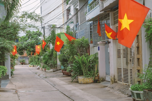 Bandeiras ao longo de uma pequena rua em Hanói. Bandeiras nacionais vietnamitas situadas na estreita faixa residencial de casas. Patriotismo dos cidadãos durante a celebração do Dia Nacional do Vietnã