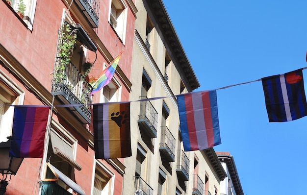 Bandeiras coloridas de diferentes comunidades gays penduradas em edifícios no distrito de chueca, em madrid, espanha