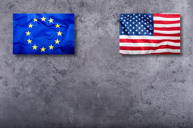 Bandeiras dos eua e da união europeia em fundo de concreto.