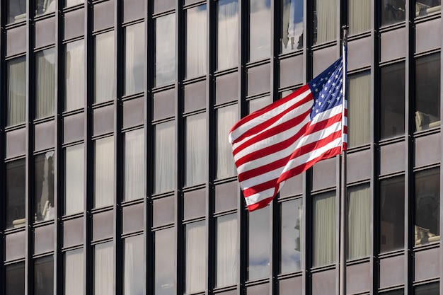 Bandeiras nacionais americanas sobre a paisagem urbana de edifício de Chicago