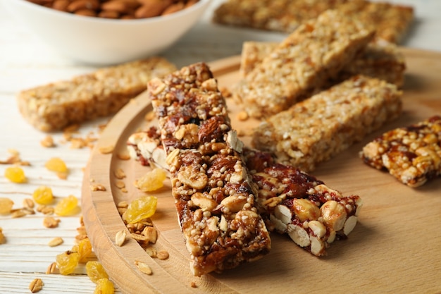 Bandeja con barras de granola y cuenco con almendras sobre fondo de madera blanca