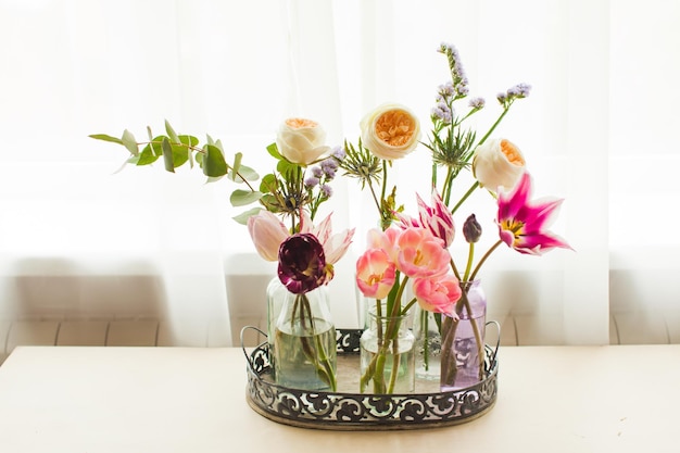 Bandeja con botellas con flores. Jarrones estilo vintage con tulipanes. Decoración del hogar