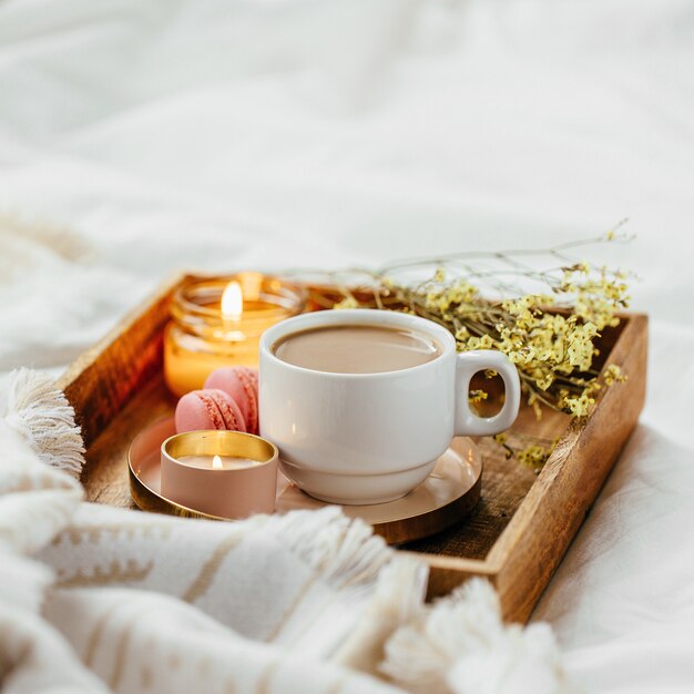 Bandeja de café y velas con cálidos cuadros escoceses sobre ropa de cama blanca. Desayuno en la cama.