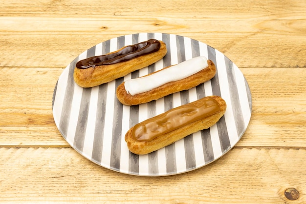 Bandeja de canutillos cubiertos con tres chocolates diferentes en plato rallado y mesa de madera sin barnizar
