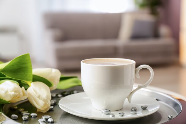 Bandeja com uma xícara de café e lindas flores na mesa