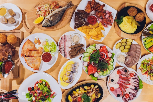 Bandeja de comida con delicioso salami, trozos de jamón en rodajas, salchichas y ensalada.