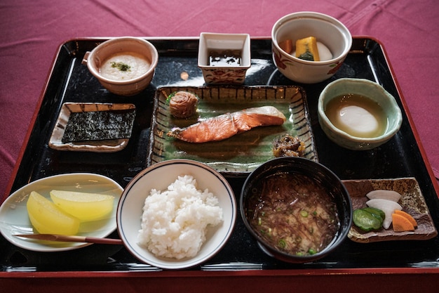 Una bandeja de comida con una variedad de alimentos que incluyen salmón, arroz y otros alimentos.