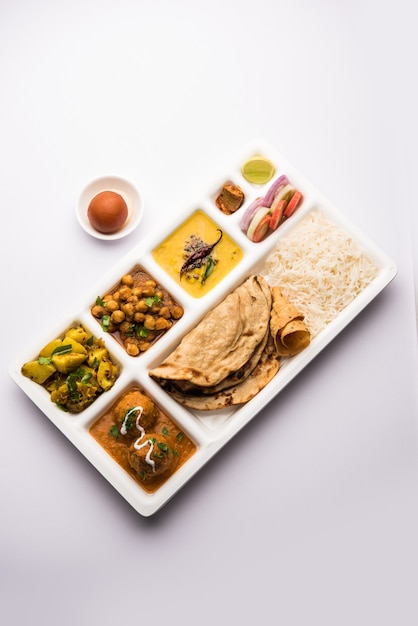 Bandeja de comida vegetariana india Thali o Parcel con compartimentos en los que se sirve Malai Kofta, chole, Dal tarka, aloo sabji seco, chapati y arroz con dulce gulab jamun