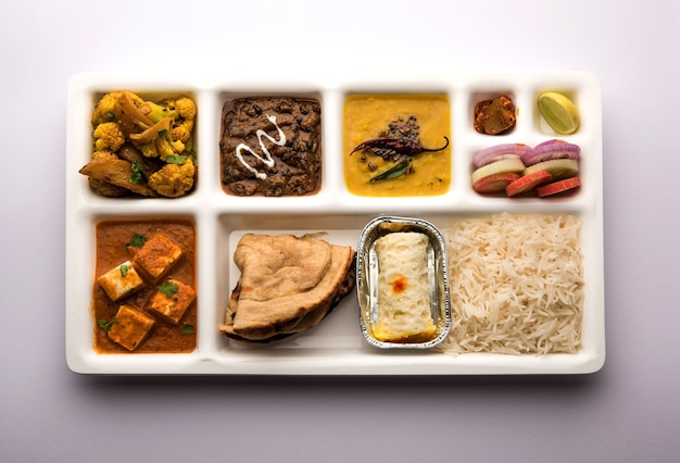 Bandeja de comida vegetariana india Thali o Parcel con compartimentos en los que se sirve paneer, dal makhani o parka, aloo-gobi sabji, chapati y arroz con dulce bengalí