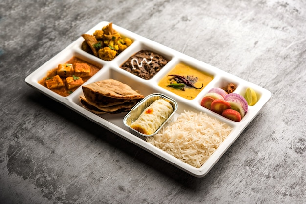 Bandeja de comida vegetariana india Thali o Parcel con compartimentos en los que se sirve paneer, dal makhani o parka, aloo-gobi sabji, chapati y arroz con dulce bengalí