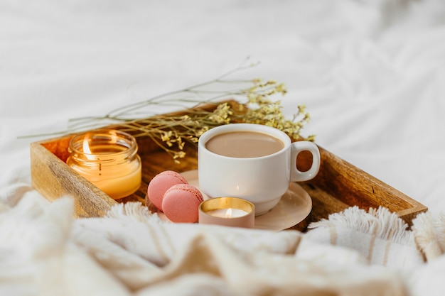 Bandeja de café e velas com manta quente sobre roupa de cama branca. Café da manhã na cama.