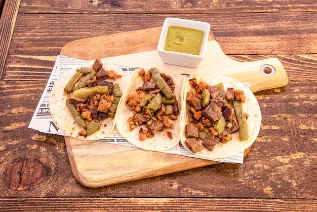 Bandeja de madeira com receita de tacos mexicanos com ensopado de carne e nopales com molho de abacate