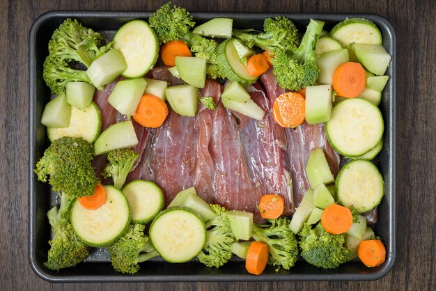 Bandeja con filetes de pescado crudo y verduras sobre mesa de madera Comida sana