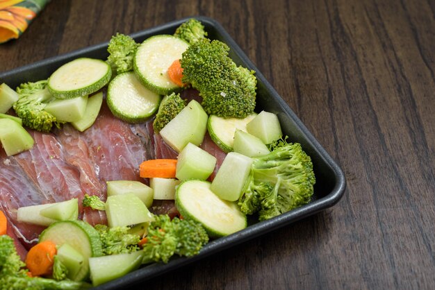 Bandeja con filetes de pescado crudo y verduras sobre mesa de madera Comida sana