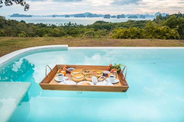 Bandeja flutuante de café da manhã na piscina do hotel de luxo ou resort tropical villa frutas croissant café e suco de laranja relaxamento exótico verão tropical viagem e conceito de férias