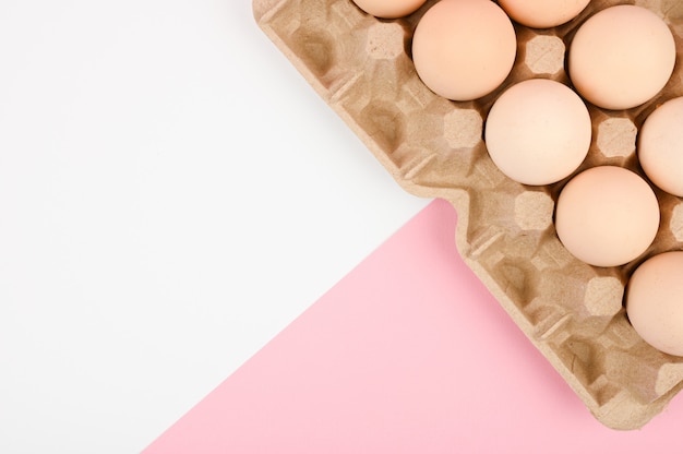 Una bandeja de huevos sobre un fondo blanco y rosa. bandeja ecológica con testículos. Tendencia minimalista, vista superior. Bandeja de huevos. Concepto de pascua.