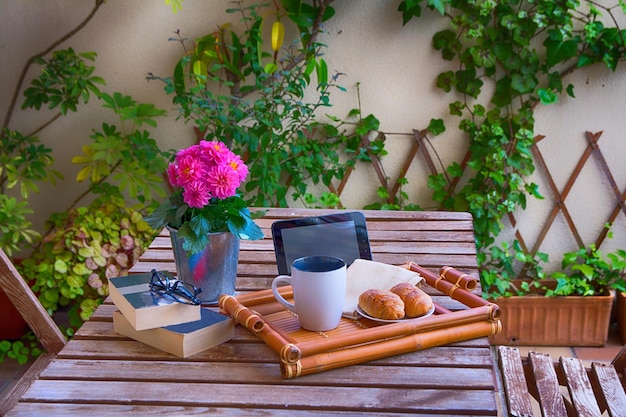 Bandeja de madera con un buen desayuno y dos libros Jardín de la casa