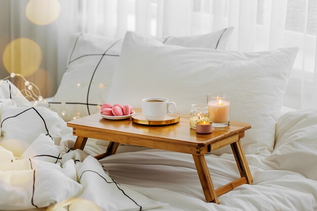 Bandeja de madera con café y velas en la cama. Desayuno en la cama. Concepto Hygge.