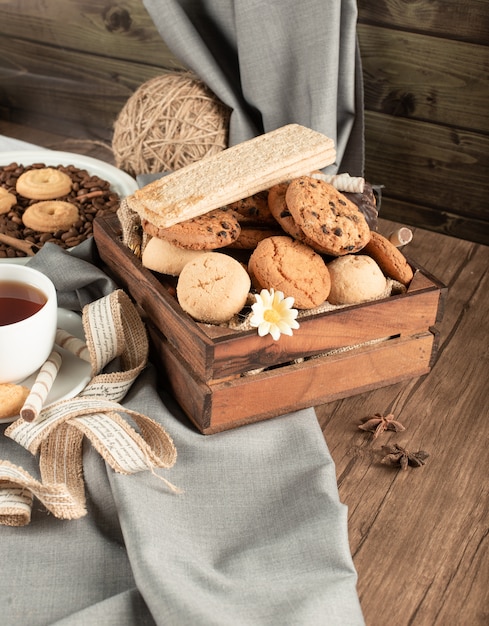 Una bandeja de madera de galletas y galletas con una taza de té.