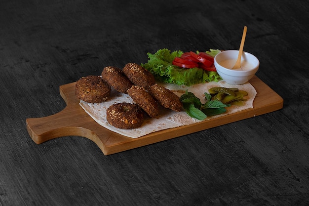 Foto una bandeja de madera con un plato de comida con un kebab y un plato de lechuga.