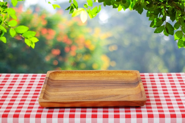 Bandeja de madera vacía en la mesa sobre árboles de desenfoque con fondo bokeh