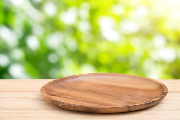 Bandeja de madera vacía sobre una mesa de madera en perspectiva encima sobre fondo borroso. Se puede utilizar como maqueta para mostrar productos de montaje o diseño.