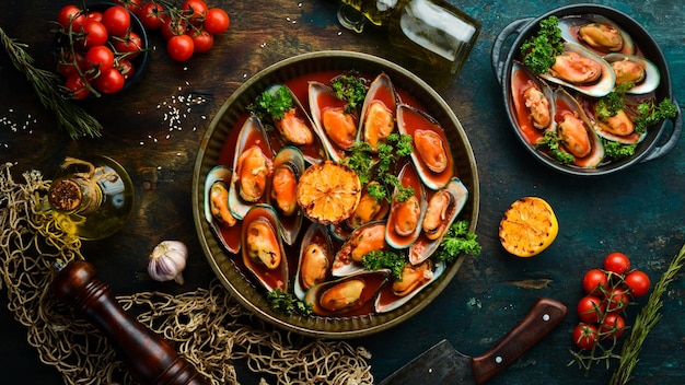 Bandeja de metal con mejillones cocinados en salsa de tomate con ajo, perejil y limón Sobre un fondo de piedra negra