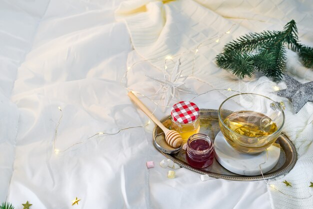 Bandeja con miel y una taza de té caliente en la cama, mañana tranquila, ambiente cálido de invierno