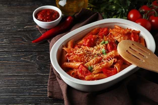 Bandeja con pasta con salsa de tomate en mesa de madera, espacio para texto