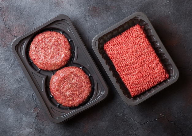 Bandeja de plástico con carne picada cruda casera hamburguesas de carne con especias y hierbas. Vista superior y.