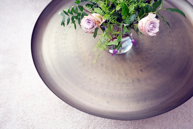 Bandeja de plata con rosas moradas en florero sobre una mesa contra la alfombra de lujo vista superior, hermosa decoración interior