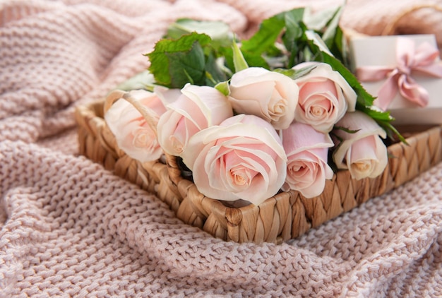 Bandeja con ramo de hermosas rosas rosadas y caja de regalo en la cama