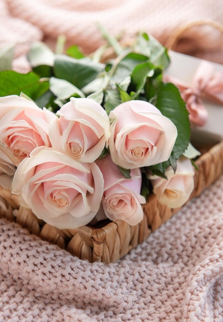 Bandeja con ramo de hermosas rosas rosadas y caja de regalo en la cama