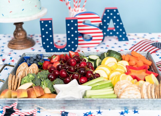 Bandeja de refrigerios con frutas frescas, verduras y salsas en la fiesta de celebración del 4 de julio.