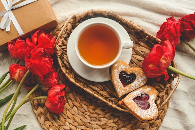 Bandeja con sabroso desayuno ramo de peonías y regalo para el Día de San Valentín en la cama