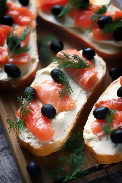 Una bandeja de sándwiches de salmón ahumado con aceitunas negras