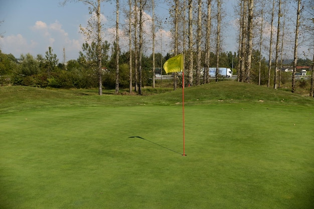 Foto bandera por agujero en el césped de golf