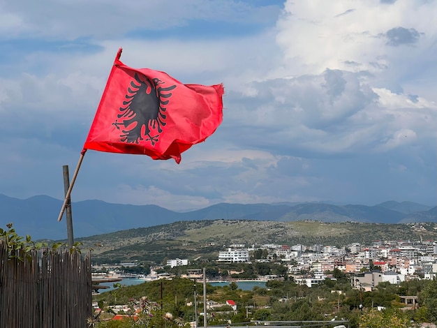 Bandera albanesa volando alto un pintoresco paisaje de pueblo de montaña