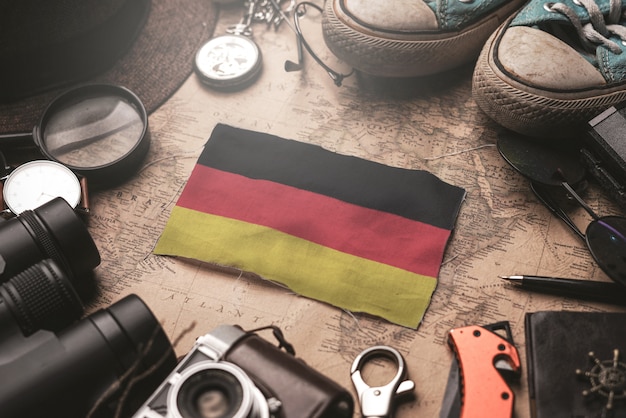 Bandera de Alemania entre los accesorios del viajero en el viejo mapa vintage. Concepto de destino turístico.