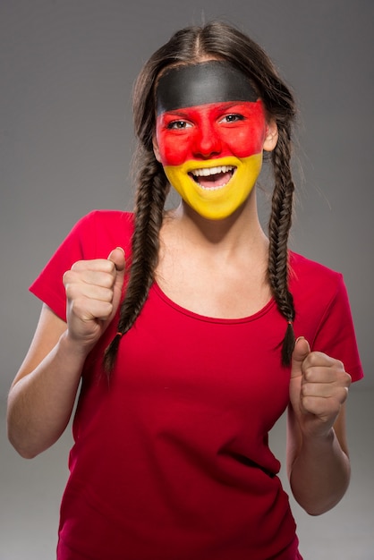 Bandera de Alemania pintada en la cara de una mujer joven.