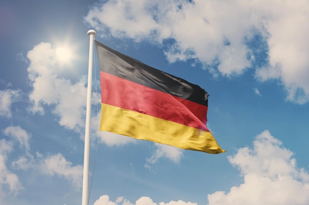 Bandera de Alemania, símbolo nacional que agita contra el cielo nublado, azul, día soleado