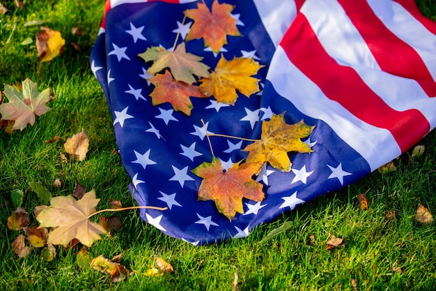 Bandera americana con hojas de arce sobre la hierba verde en otoño