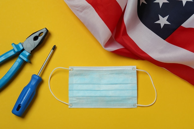 Bandera americana, máscara y herramientas sobre fondo amarillo